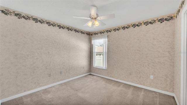 carpeted empty room with baseboards and a ceiling fan