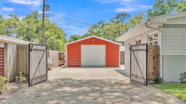 detached garage featuring gravel driveway, a gate, and fence