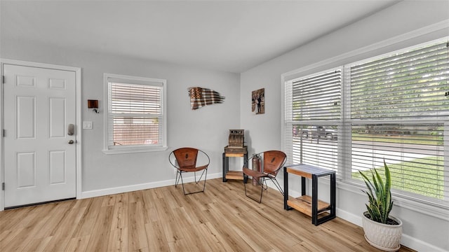 living area with a healthy amount of sunlight, light wood-style flooring, and baseboards