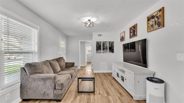 living area featuring visible vents, light wood-style flooring, and baseboards