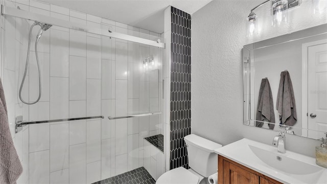 bathroom featuring vanity, toilet, a textured wall, and a stall shower