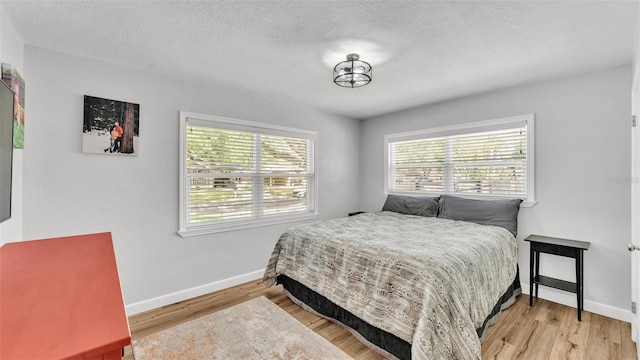 bedroom featuring baseboards, a textured ceiling, and wood finished floors