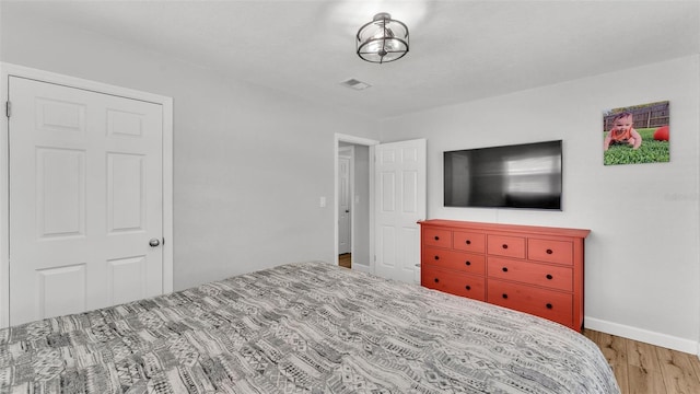 bedroom with wood finished floors, visible vents, and baseboards