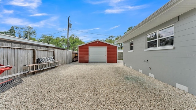 detached garage with gravel driveway, a storage shed, and fence