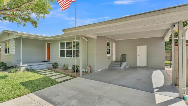 view of front of property with an attached carport, concrete driveway, a front yard, and fence