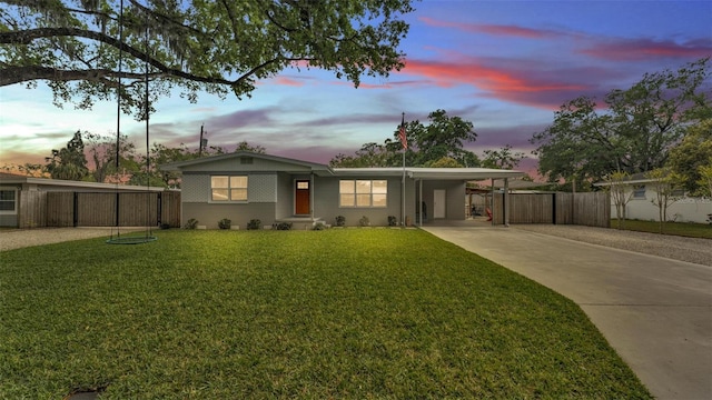 view of front of property with a carport, a yard, fence, and driveway