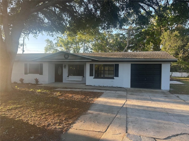 ranch-style house featuring concrete driveway, brick siding, and a garage