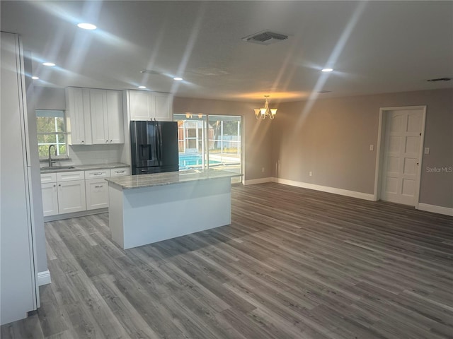 kitchen with visible vents, a sink, black fridge with ice dispenser, white cabinets, and a chandelier