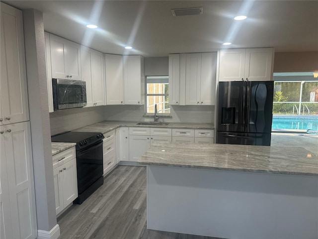 kitchen with a sink, visible vents, black appliances, and white cabinets