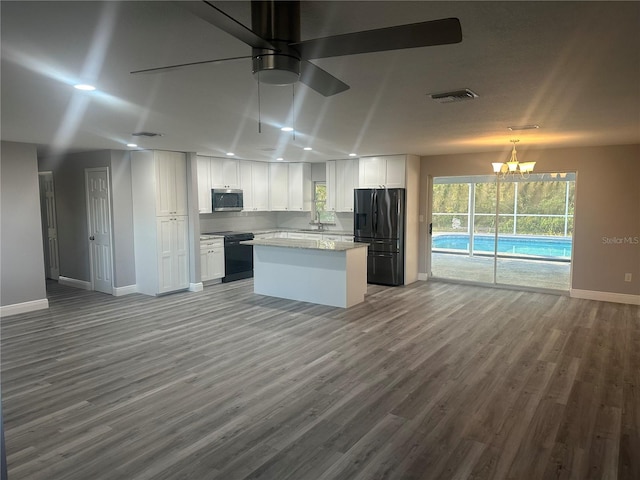 kitchen featuring visible vents, black appliances, open floor plan, a center island, and white cabinetry