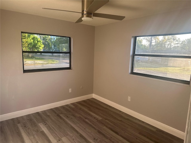 spare room featuring baseboards, dark wood finished floors, and a ceiling fan