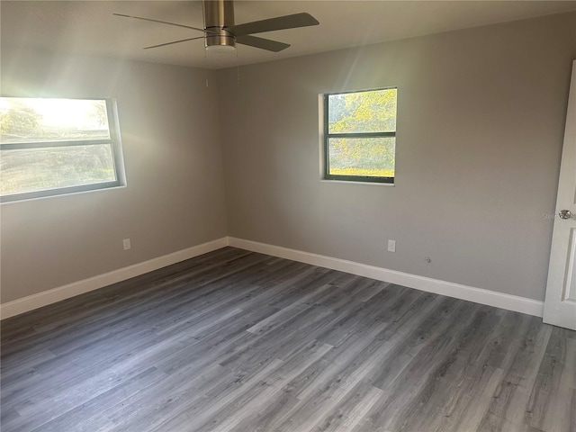 spare room with baseboards, a ceiling fan, and dark wood-style flooring