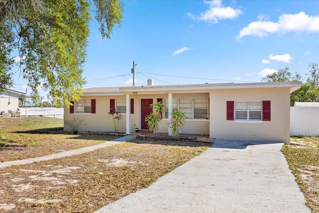 single story home featuring stucco siding, concrete driveway, a front yard, and fence