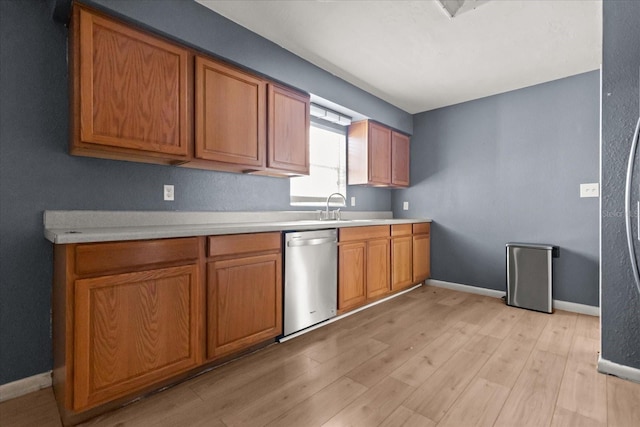 kitchen with a sink, stainless steel dishwasher, light wood-style flooring, and brown cabinetry