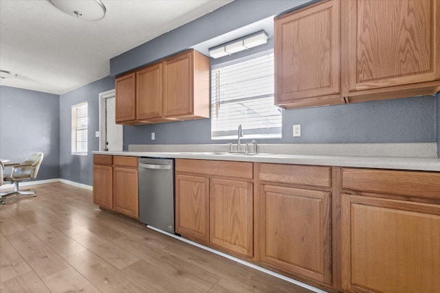 kitchen with a healthy amount of sunlight, dishwasher, light countertops, and a sink