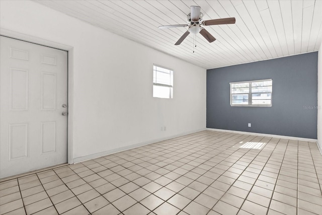 empty room featuring wooden ceiling, light tile patterned floors, a ceiling fan, and baseboards