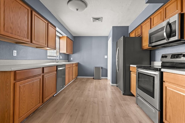 kitchen with light countertops, light wood-style floors, baseboards, and stainless steel appliances