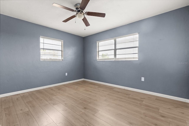 spare room with plenty of natural light, baseboards, light wood-type flooring, and ceiling fan