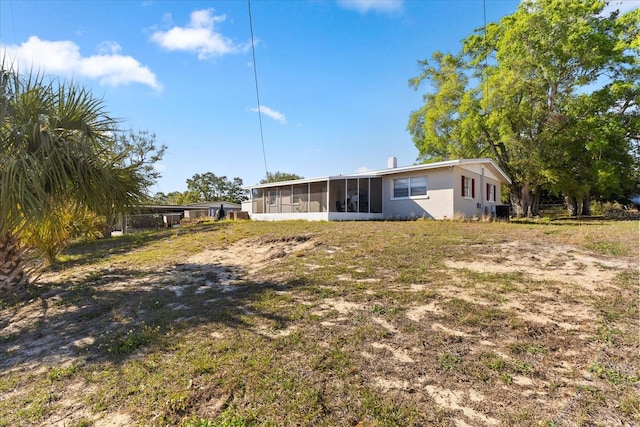 back of property featuring a sunroom and stucco siding