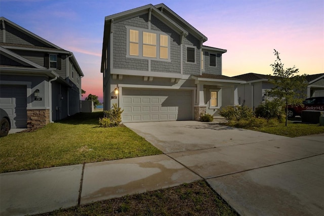 craftsman-style home with concrete driveway, a lawn, stucco siding, stone siding, and an attached garage