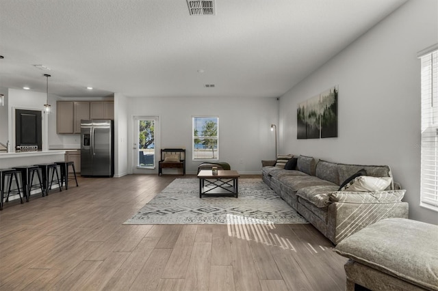 living area featuring recessed lighting, wood finished floors, visible vents, and baseboards