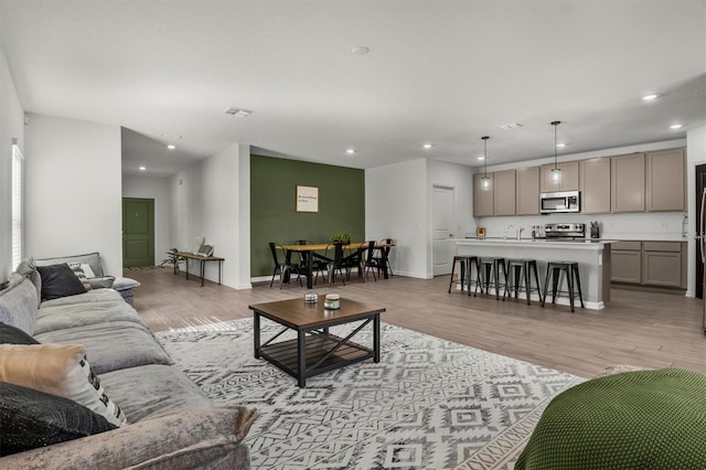 living area featuring visible vents, recessed lighting, baseboards, and light wood finished floors