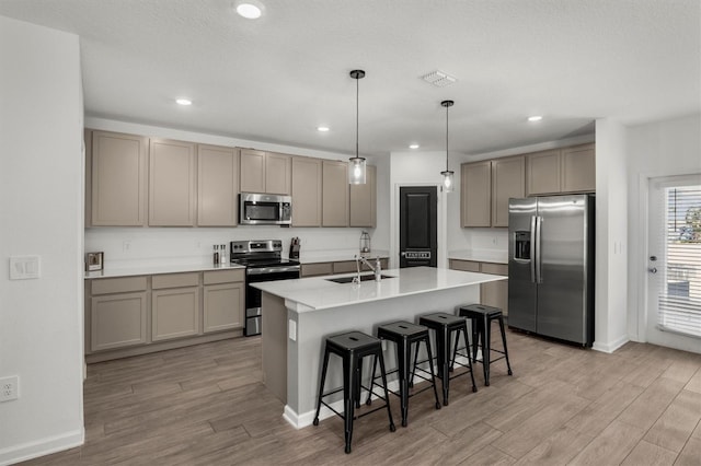 kitchen with visible vents, a breakfast bar, light wood-type flooring, stainless steel appliances, and a sink