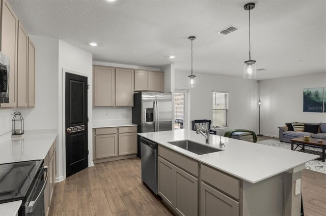 kitchen featuring visible vents, gray cabinets, a sink, wood finished floors, and stainless steel appliances