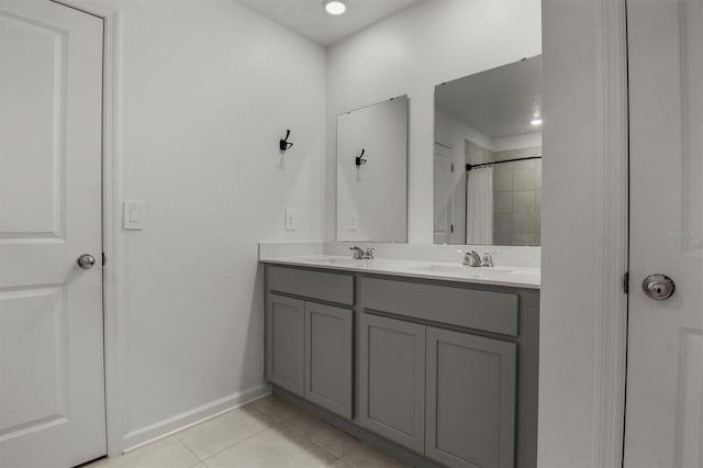 bathroom with tile patterned floors, double vanity, baseboards, and a sink