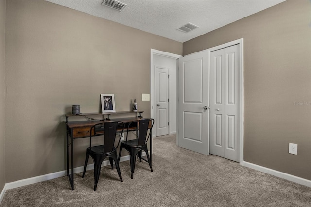 office area with light carpet, visible vents, a textured ceiling, and baseboards