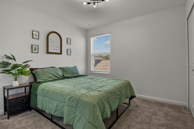 carpeted bedroom with a textured ceiling and baseboards