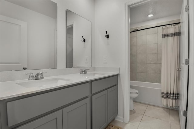 bathroom with a sink, toilet, double vanity, and tile patterned flooring