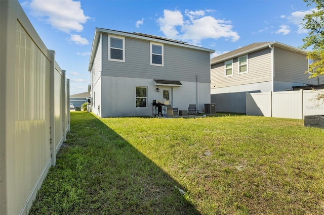 rear view of property with central air condition unit, stucco siding, a yard, and fence