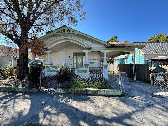 exterior space featuring a fenced front yard, a porch, a carport, driveway, and a gate