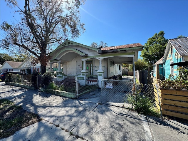 view of front of property with driveway, a fenced front yard, covered porch, metal roof, and an attached carport