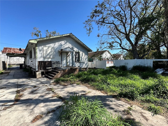 bungalow featuring concrete driveway and fence