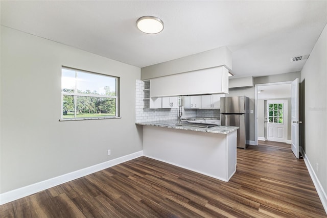 kitchen featuring visible vents, a peninsula, freestanding refrigerator, and dark wood-type flooring