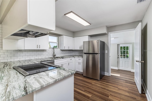 kitchen featuring white cabinetry, light stone countertops, tasteful backsplash, and freestanding refrigerator