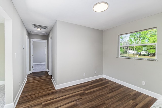 unfurnished room with baseboards, visible vents, and dark wood-style flooring