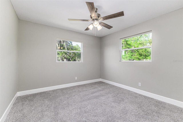 carpeted spare room with baseboards, a healthy amount of sunlight, and a ceiling fan