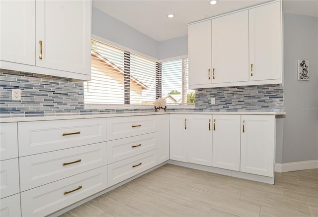 kitchen featuring backsplash, white cabinets, and light countertops