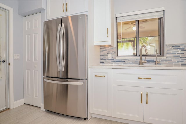 kitchen with decorative backsplash, white cabinets, light countertops, and freestanding refrigerator