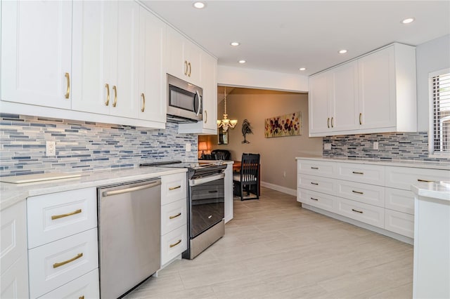 kitchen with tasteful backsplash, appliances with stainless steel finishes, white cabinets, and light countertops