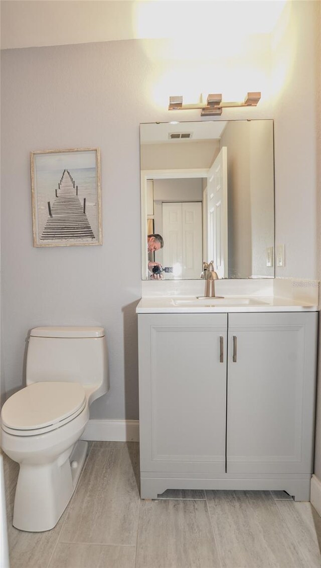 bathroom featuring visible vents, baseboards, toilet, and vanity