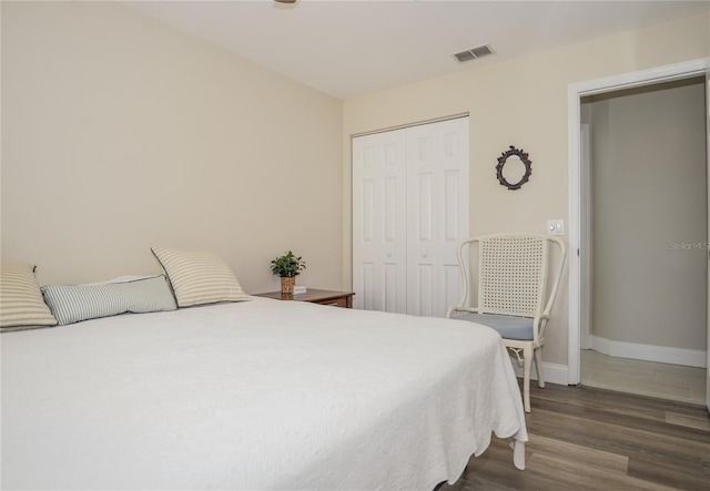 bedroom with visible vents, baseboards, a closet, and dark wood finished floors