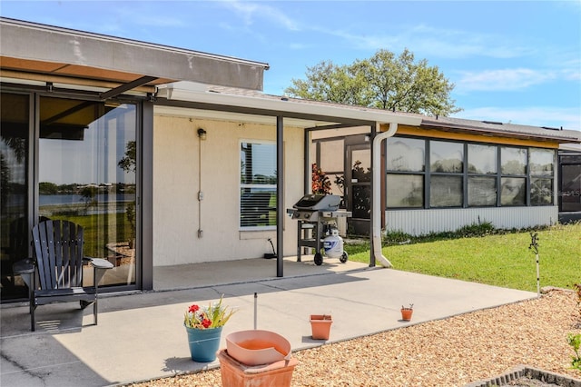 rear view of house featuring a yard, a patio, and a sunroom