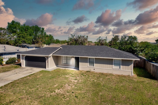 single story home featuring a front lawn, concrete driveway, fence, and a garage