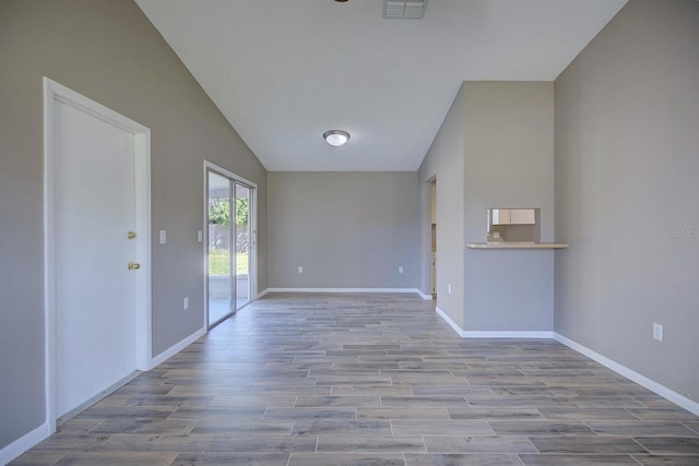 unfurnished living room with visible vents, baseboards, lofted ceiling, and wood finished floors