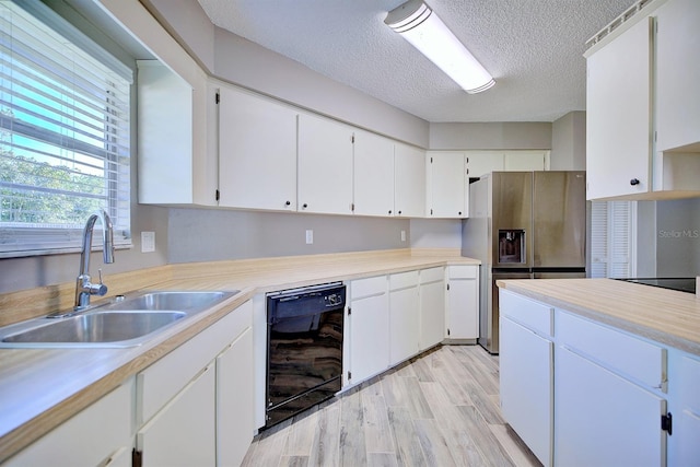 kitchen with stainless steel fridge with ice dispenser, white cabinetry, light countertops, and a sink