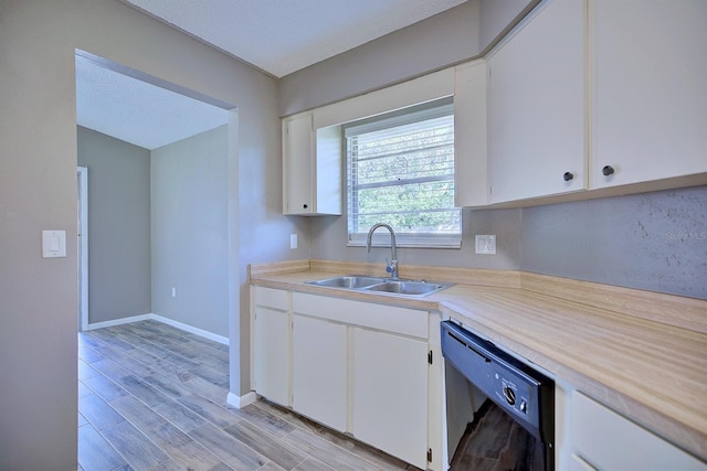 kitchen with dishwasher, light countertops, white cabinets, and a sink